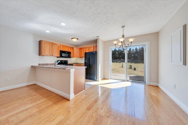 kitchen with light wood finished floors, baseboards, light countertops, a peninsula, and black appliances