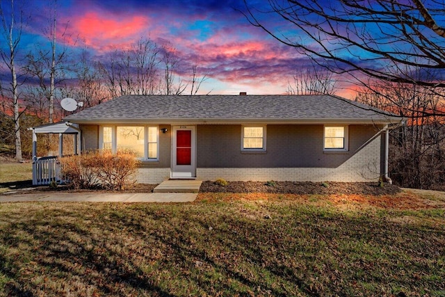 ranch-style house with brick siding, a front lawn, and a shingled roof