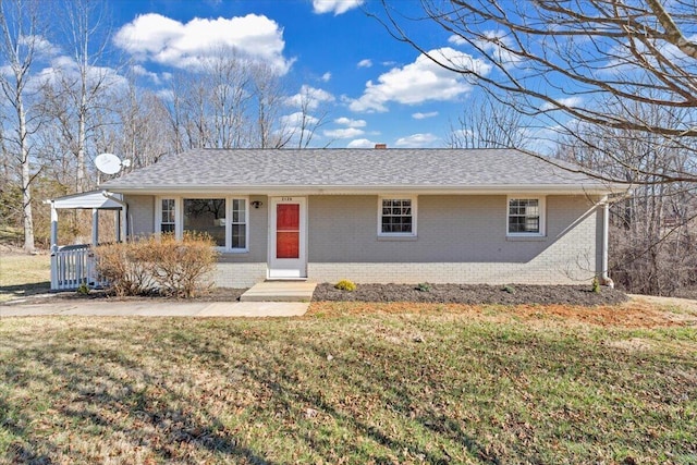 single story home featuring brick siding, a front lawn, and a shingled roof