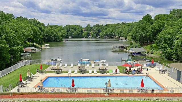 pool with fence, a patio, and a water view