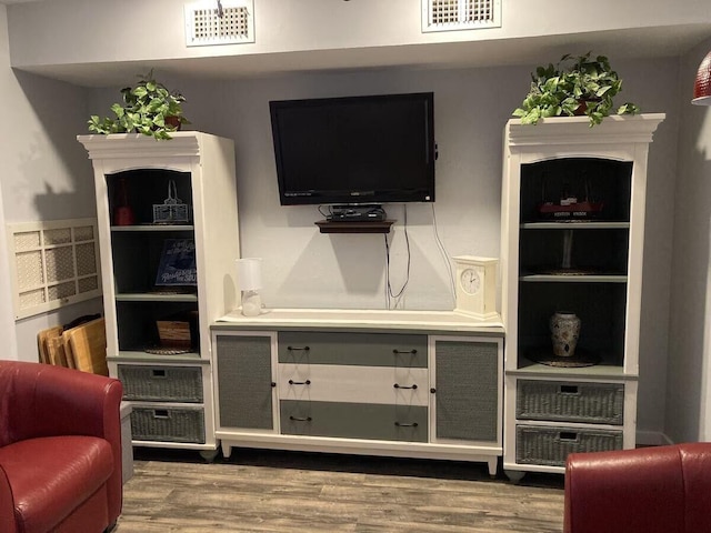living area featuring visible vents and wood finished floors