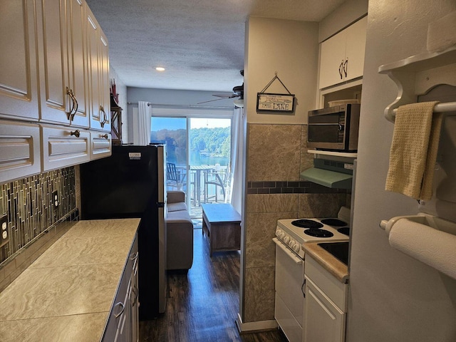 kitchen with appliances with stainless steel finishes, light countertops, white cabinetry, tile walls, and dark wood-style floors