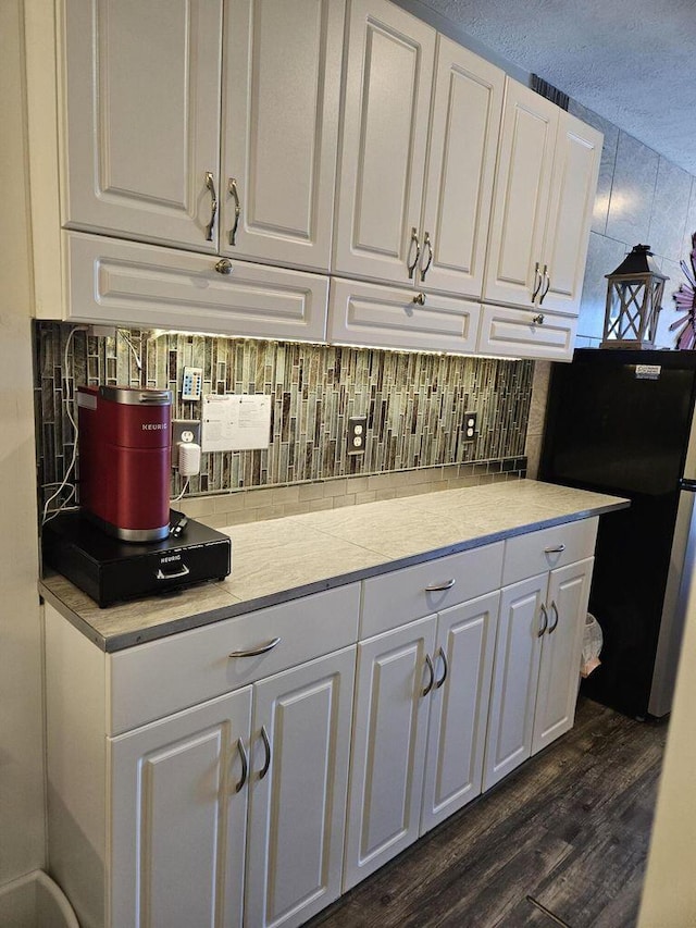 bar featuring freestanding refrigerator, dark wood-style flooring, and tasteful backsplash