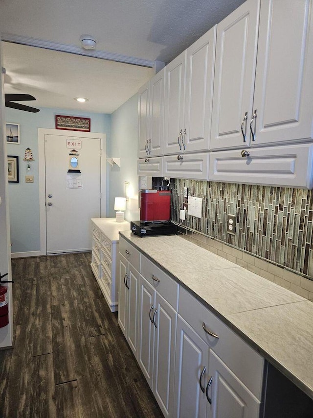 kitchen with light countertops, white cabinets, dark wood finished floors, and tasteful backsplash