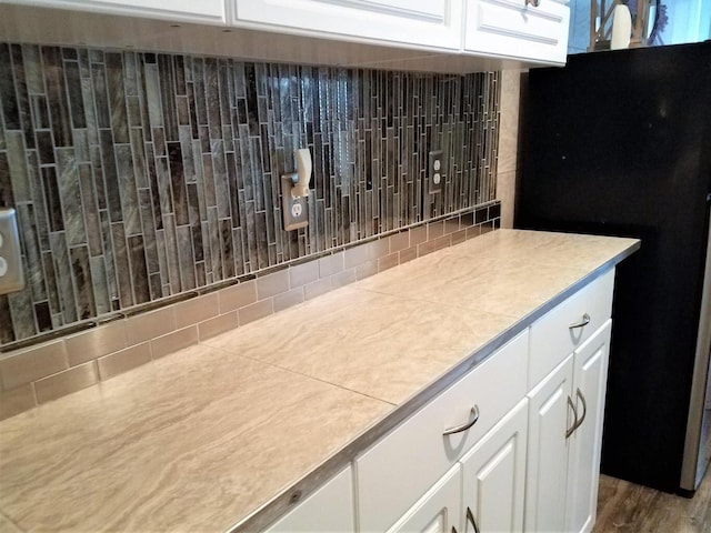 room details with light countertops, white cabinets, and freestanding refrigerator