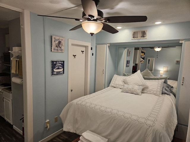 bedroom featuring a ceiling fan, visible vents, and dark wood-type flooring