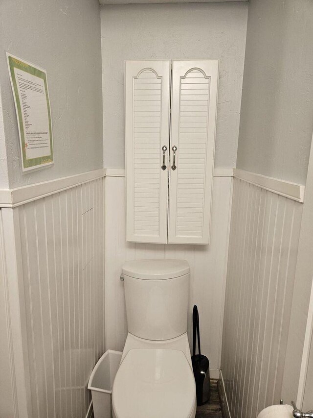 bathroom featuring a wainscoted wall and toilet