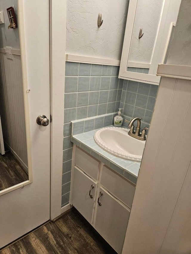 bathroom with vanity, wood finished floors, and tasteful backsplash