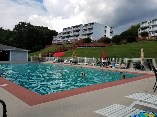 community pool with a yard, a patio, and fence