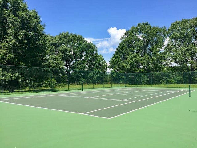 view of tennis court featuring community basketball court and fence