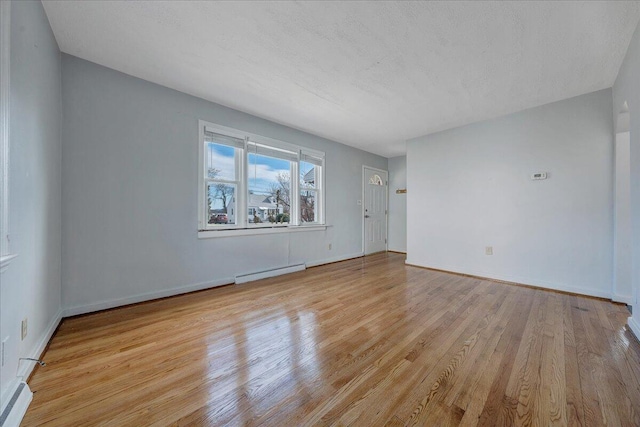 empty room with a baseboard radiator, wood finished floors, and baseboards