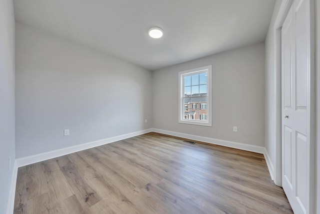 unfurnished bedroom featuring wood finished floors, visible vents, and baseboards