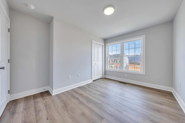 unfurnished bedroom with baseboards, a closet, visible vents, and wood finished floors