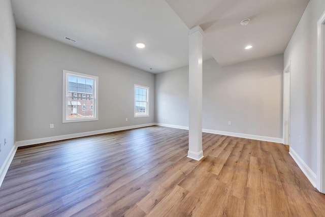 interior space with baseboards, light wood finished floors, visible vents, and ornate columns