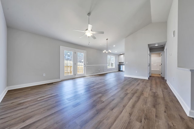 unfurnished living room featuring ceiling fan with notable chandelier, dark wood finished floors, visible vents, baseboards, and vaulted ceiling