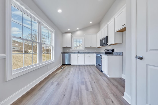 kitchen with white cabinets, appliances with stainless steel finishes, baseboards, and light wood-style floors