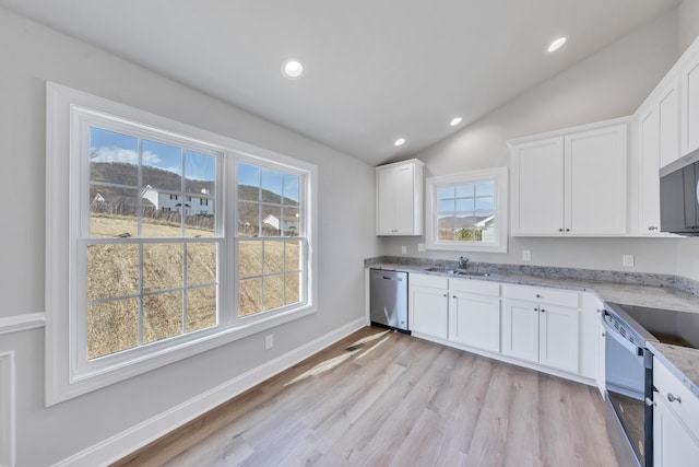 kitchen featuring a sink, stainless steel appliances, white cabinets, light stone countertops, and vaulted ceiling