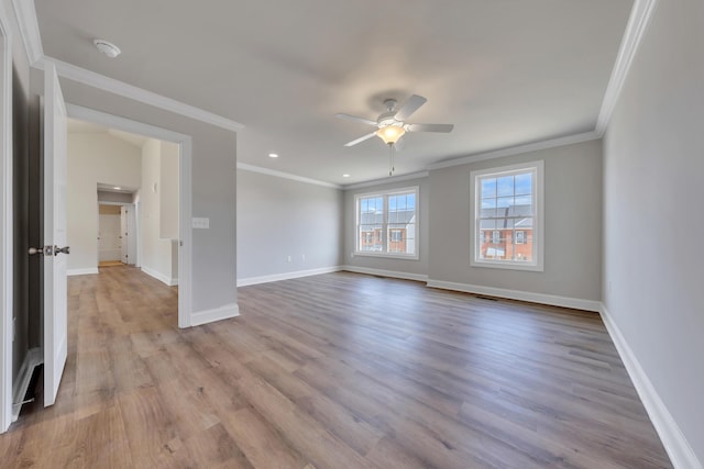 spare room with ceiling fan, wood finished floors, baseboards, and ornamental molding