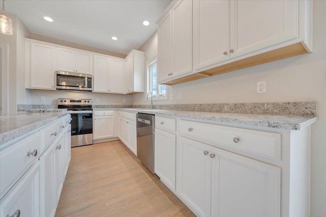 kitchen featuring light wood-style flooring, recessed lighting, stainless steel appliances, white cabinets, and light stone countertops