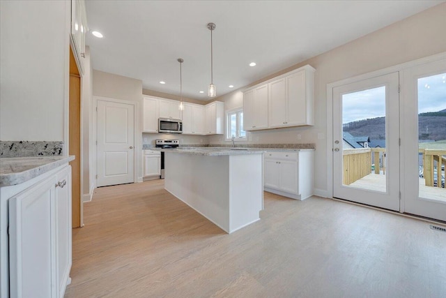 kitchen with light wood-type flooring, a kitchen island, white cabinetry, and stainless steel appliances