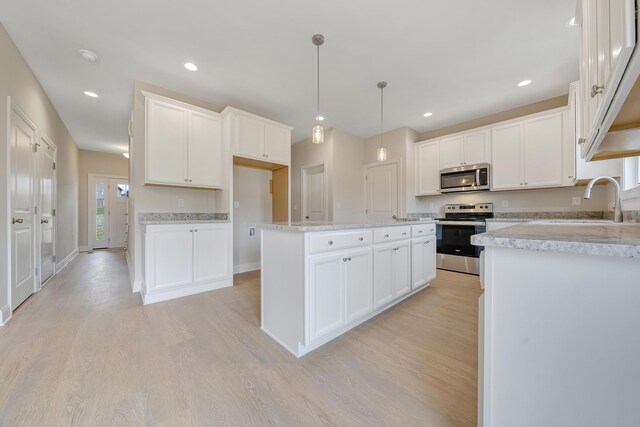 kitchen featuring light wood-style floors, appliances with stainless steel finishes, a kitchen island, and a sink