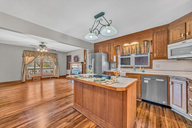 kitchen with a kitchen island, open floor plan, stainless steel appliances, light countertops, and a fireplace