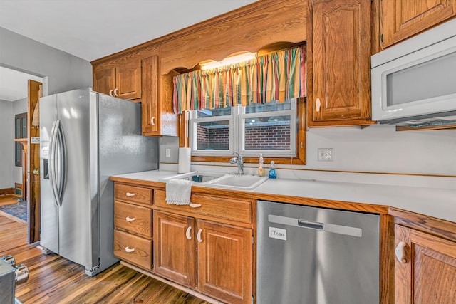 kitchen with appliances with stainless steel finishes, brown cabinets, light countertops, and a sink