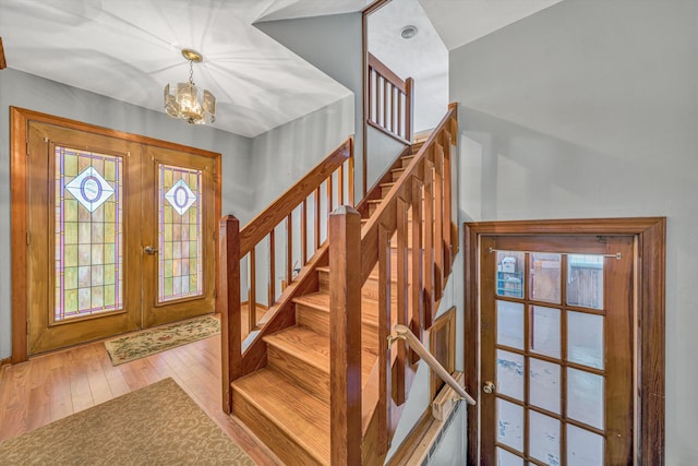 foyer featuring a notable chandelier, stairs, hardwood / wood-style floors, and french doors