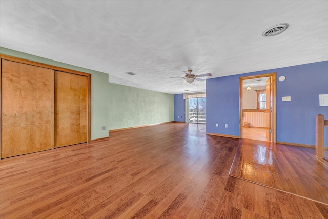 unfurnished living room featuring ceiling fan, wood finished floors, visible vents, and baseboards