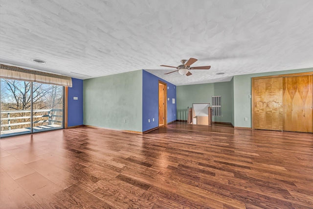 unfurnished living room featuring a textured ceiling, wood finished floors, visible vents, and baseboards