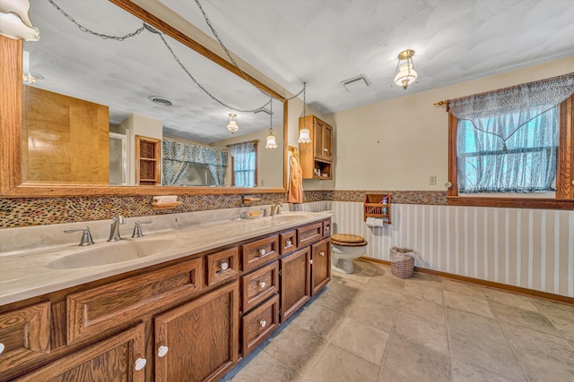 bathroom with a wealth of natural light, wainscoting, a sink, and visible vents