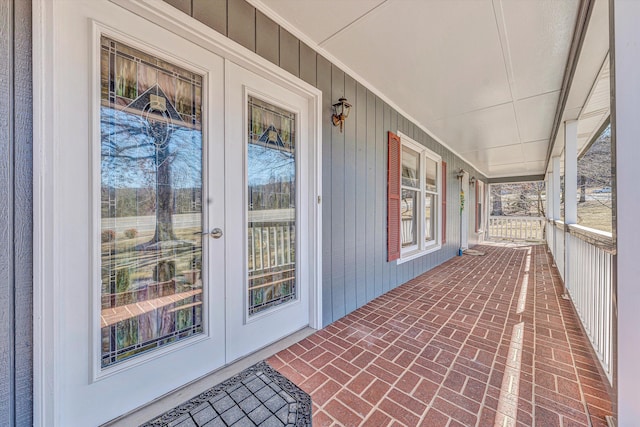 property entrance featuring a porch, board and batten siding, and french doors