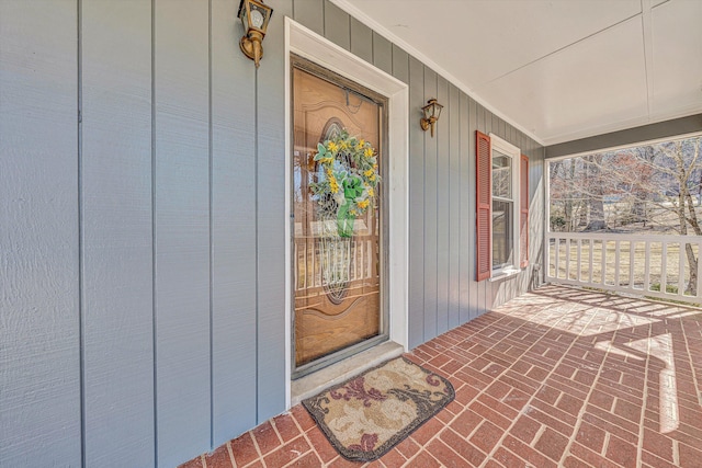 property entrance with covered porch and board and batten siding