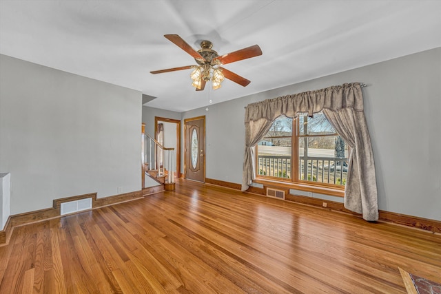 unfurnished room featuring stairs, wood finished floors, and visible vents