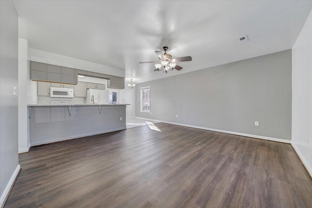 unfurnished living room featuring dark wood finished floors, baseboards, and ceiling fan with notable chandelier