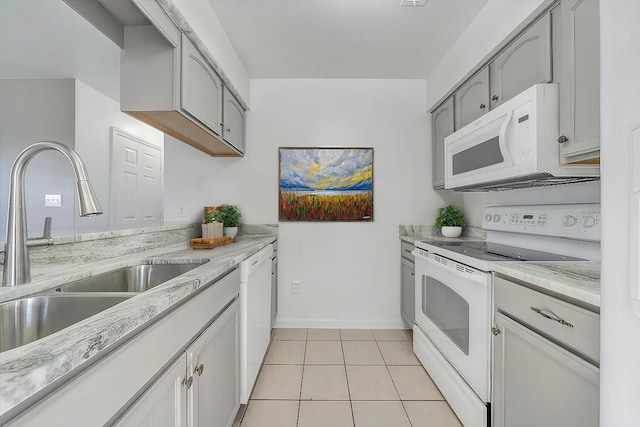 kitchen with white appliances, light tile patterned floors, baseboards, light stone counters, and a sink