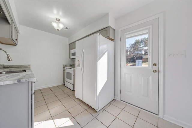 kitchen featuring white appliances, light tile patterned floors, visible vents, light countertops, and a sink