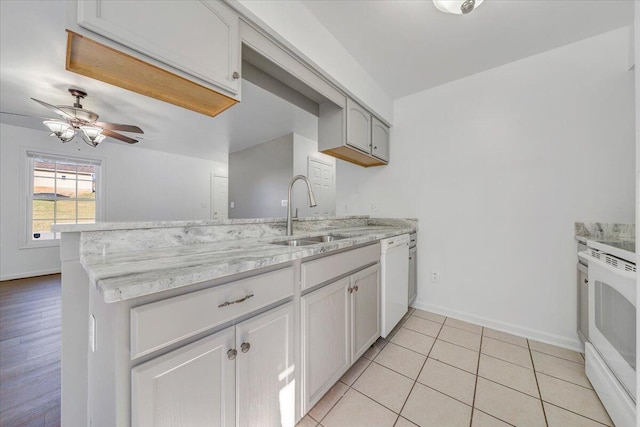 kitchen with white appliances, light tile patterned floors, baseboards, a peninsula, and a sink