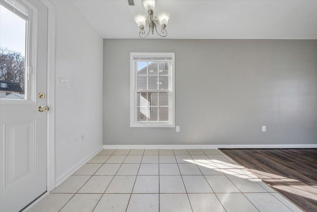 unfurnished dining area with a notable chandelier, baseboards, and light tile patterned floors