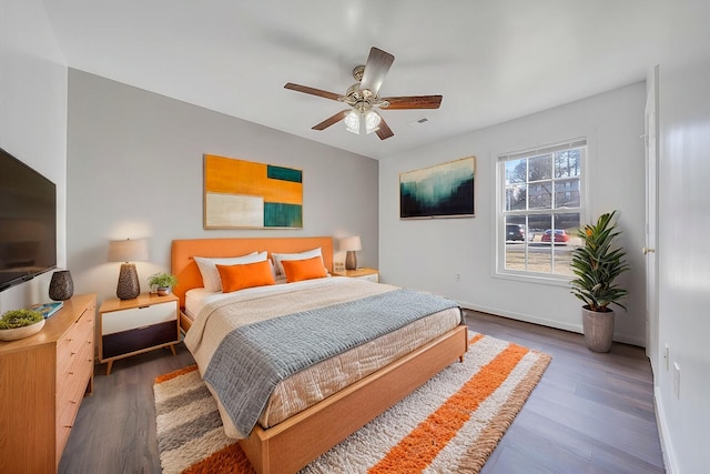 bedroom featuring ceiling fan, baseboards, and wood finished floors