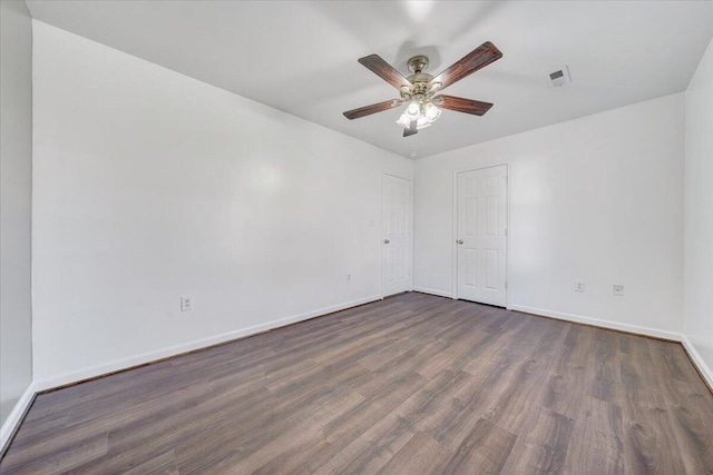 unfurnished room with dark wood-style flooring, visible vents, ceiling fan, and baseboards