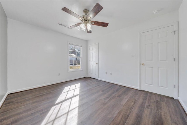 spare room featuring dark wood finished floors, visible vents, and baseboards