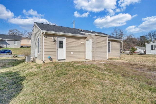 rear view of property featuring a yard and central AC unit