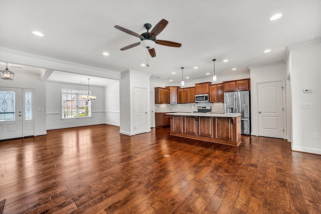 kitchen with stainless steel appliances, open floor plan, light countertops, backsplash, and dark wood finished floors