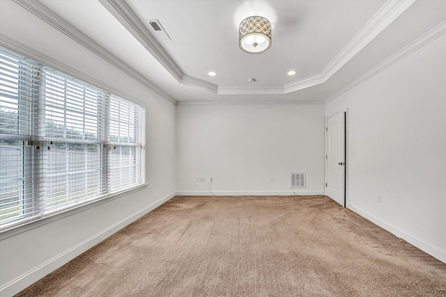 spare room with light carpet, visible vents, a tray ceiling, and baseboards