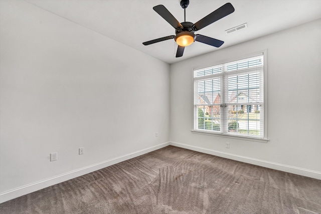 carpeted empty room featuring visible vents, baseboards, and ceiling fan