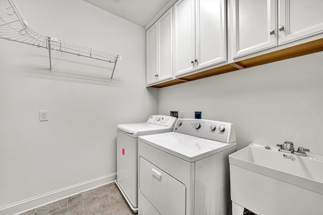 clothes washing area featuring washing machine and clothes dryer, a sink, cabinet space, and baseboards