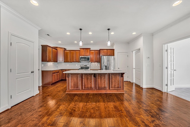 kitchen featuring appliances with stainless steel finishes, a center island with sink, ornamental molding, and decorative backsplash