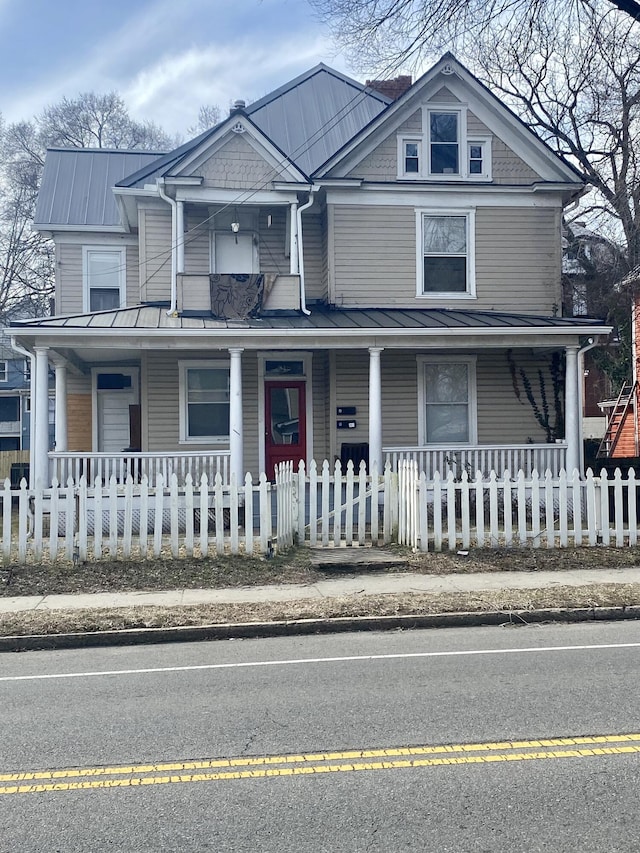 view of front facade featuring a fenced front yard, covered porch, and metal roof