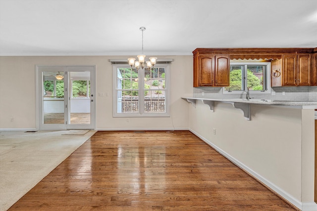 5653 Orchard Valley Cir, Roanoke, VA 24018 - kitchen featuring a breakfast bar area, light countertops, a chandelier, brown cabinets, and baseboards